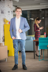 Young businessman in blue jacket standing at office