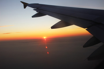Airplane wing with sunset in background.