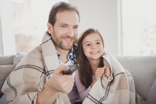Close-up portrait of his he her she nice cute lovely sweet attractive cheerful pre-teen girl handsome bearded dad daddy sitting on divan watching tv-show cartoon in modern light white interior room