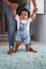 baby learning how to walk holding mum's hands