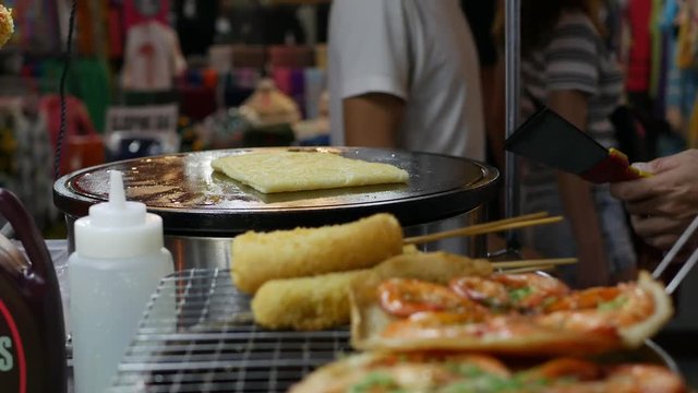 Seller fries pancakes with bananas in the Vietnamese night market. Asian street food. 4k