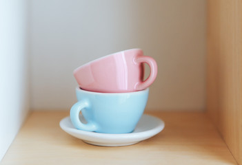 Ceramic cups blue and pink on a wooden shelf