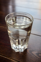 Large glass of clear Lemonade cold drink on a dark wooden table.  Close up view