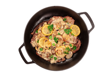 Scallopine di vitello, a traditional Italian dish of veal, with a mushroom sauce, lemons, and herbs, shot from the top in a pan, isolated on a white background with a clipping path