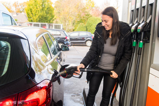 Junge Frau beim Tanken ihres PKW an einer Tankstelle