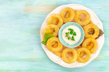 Squid rings with a mayo dip, shot from the top on a blue background with a place for text