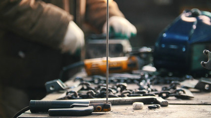 Industrial. Construction site. The man worker grinding. Tools and chains on the table