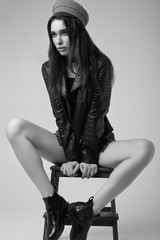 Fashion brunette woman wearing a leather jacket and red hat