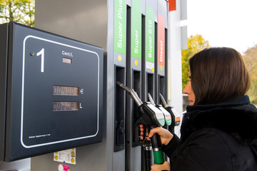 Junge Frau beim Tanken ihres PKW an einer Tankstelle