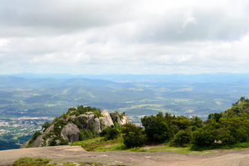 Obraz premium Rocky and green landscape of the mountains of Pedra Grande park in Atibaia, Sao Paulo, Brazil. In the back ground aerial view of the city of Atibaia