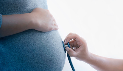 Fototapeta premium Close up doctor checking belly of pregnant woman with stethoscope.