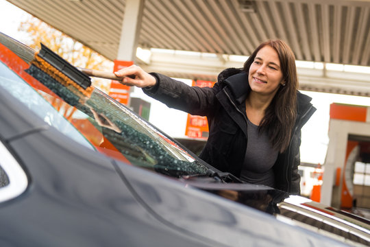 Junge Frau reinigt die Frontscheibe ihres Autos
