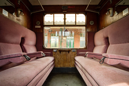 Colchester / Great Britain - May 12, 2013: Interior shot of vintage railway carriage showing seating and window.  Old station building can be seen through window.