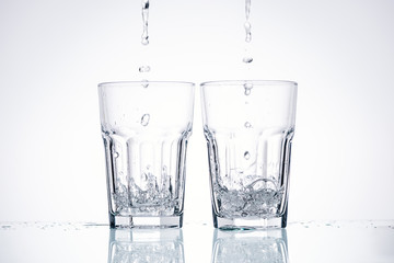 water pouring in glasses on white background with backlit