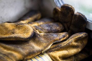 Pair of yellow greasy workmens gloves covered in dirt.