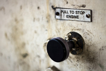Pull to stop engine sign above a pull control.  Mucky and greasy heritage sign on railway engine.