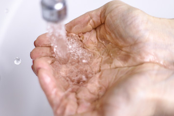 The water from the tap accumulated in the handful. On the white background.