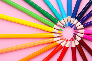 Circle formed by colored pencils on pink background