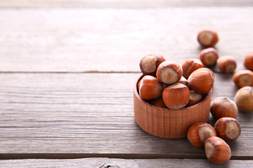Delicious hazelnut in the wooden bowl on a grey background