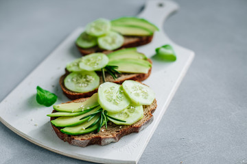 Healthy food sandwiches with avocado and cucumbers on a gray background