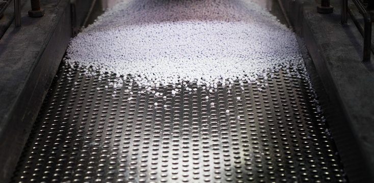 White pellets of thermal polymer being sorted on the production line as part of the industrial manufacturing process.