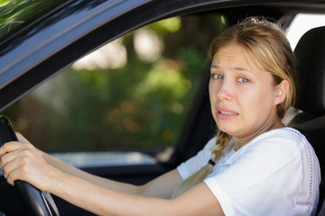 woman driver in car with expression of regret