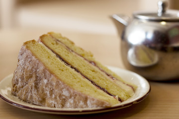 Victoria sponge cake with metal teapot in the background.  Afternoon tea, cake, dessert, treat food concepts.