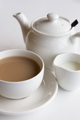 Cup of tea  in a white teacup on a saucer with milk in a jug and teapot.  Teatime, take a break, tea shop, coffee shop culture concepts.
