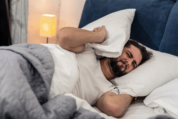 Cheerless unhappy man wanting to stay in bed