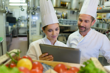 restaurant manager showing tablet to chef
