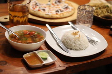 Sop Janda, the typical indonesian beef soup, served with rice and sambal on the wood table