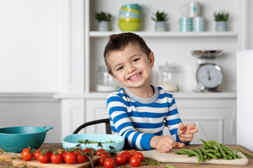 Portrait of smiling boy with cherry tomatoes and green beans at home