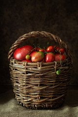 Fototapeta na wymiar Large wicker basket with a variety of ripe organic tomatoes