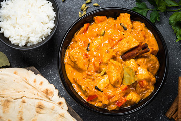 Chicken tikka masala with rice on black top view.