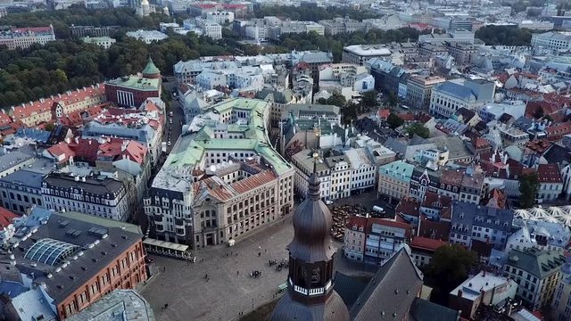 European architecture top view to the colored rooftops and narrow streets with moving cars and people background. Sightseeing from the drone camera. Casual life, day time in the square in latvian town