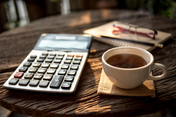 Close-Up Of Document With Calculator And coffee On Office Desk