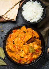 Chicken tikka masala with rice on black top view.