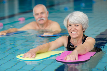 happy senior couple taking swimming lessons