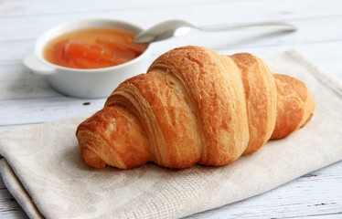 croissant on a napkin, jam, spoon, light background