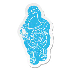 cartoon distressed sticker of a curious boy rubbing eyes in disbelief wearing santa hat