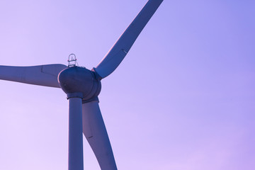 silhouette of wind turbine blades against a purple sky