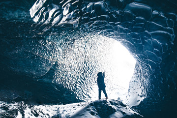 Man pointing at the light at the end of tunnel in ice cave vatnajokull national park Iceland