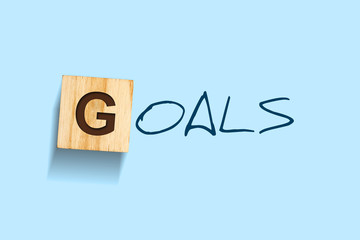 Goals. Words written on a wooden block. Blue background. Isolated. Business.