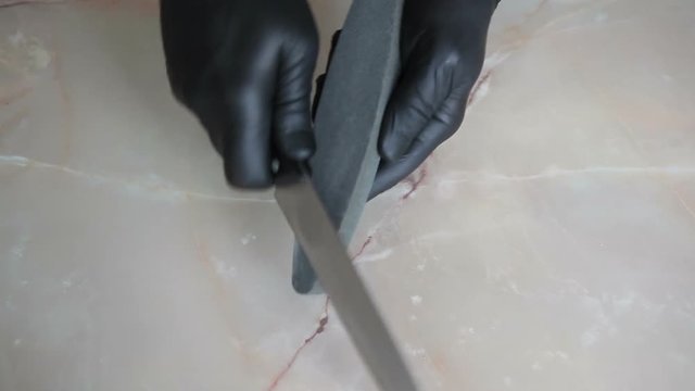 Cook sharpens a kitchen knife. View from above.