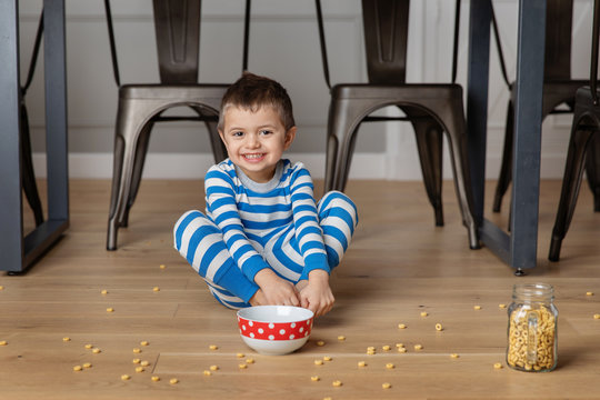 Cute boy eating cereal on kichen floor