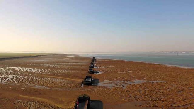 Aerial sequence featuring derelict WWII barges along the Essex coastline. Situated along the Blackwater River, part of the Dengie Peninsula and low-lying marshes near Bradwell in Essex.