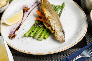 Fried fish with appetizers and white wine. Caucasian cuisine.