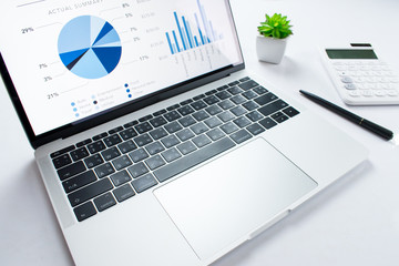 Side view of the financial business laptop on a white table with a calculator on the side. Business concept.