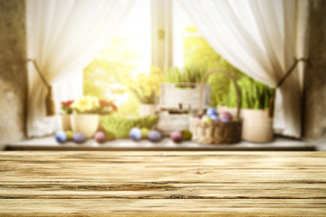Wooden table of free space for your decoration. Spring window background. Easter eggs and flowers on window sill. 