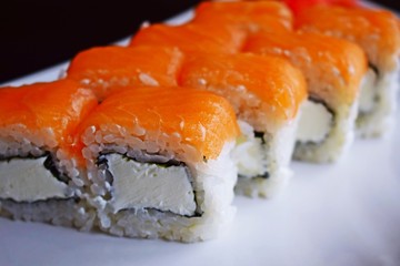 Delicious fresh rolls, Philadelphia, on white plate and black background.